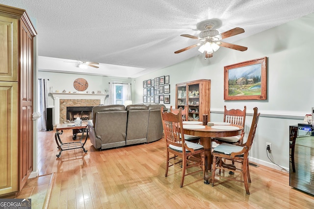 55 Hubbard Ct, Newnan, GA 30263 - dining room with a ceiling fan, light wood-style flooring, a textured ceiling, and a premium fireplace