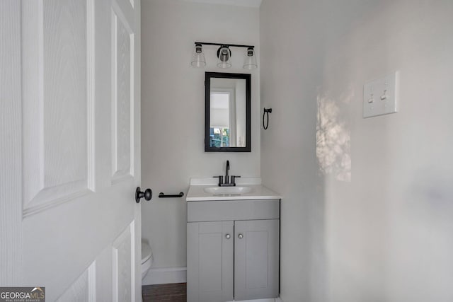 half bathroom featuring toilet, vanity, and baseboards