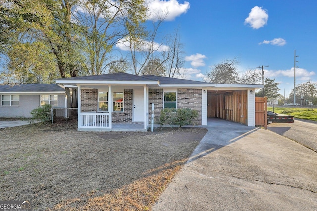 ranch-style home with covered porch, brick siding, driveway, and an attached carport
