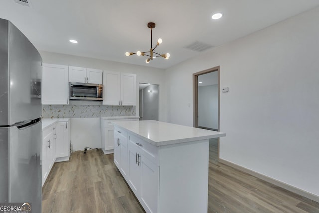 1601 Coventry St, Savannah, GA 31415 - kitchen with appliances with stainless steel finishes, tasteful backsplash, white cabinetry, a chandelier, and light wood-style flooring