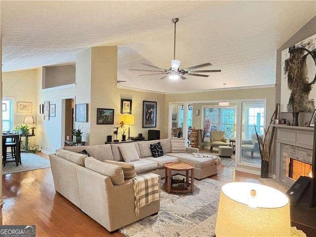 4025 Mcdowell Dr, Acworth, GA 30101 - living room with a ceiling fan, a textured ceiling, light wood-style flooring, and a warm lit fireplace