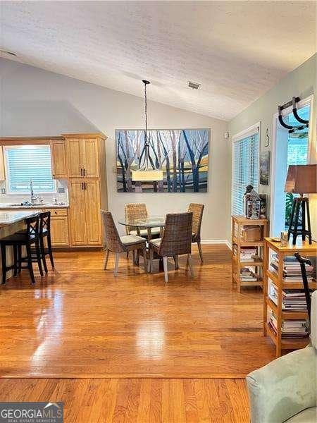 4025 Mcdowell Dr, Acworth, GA 30101 - dining room featuring lofted ceiling, light wood-style floors, and a textured ceiling
