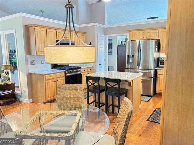 4025 Mcdowell Dr, Acworth, GA 30101 - kitchen featuring appliances with stainless steel finishes, light wood-style flooring, a breakfast bar area, light brown cabinetry, and ornamental molding