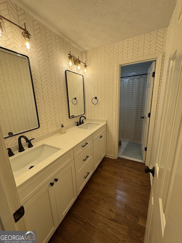 3146 Weymouth Dr, Marietta, GA 30062 - bathroom featuring wallpapered walls, wood finished floors, a textured ceiling, double vanity, and a shower with shower curtain