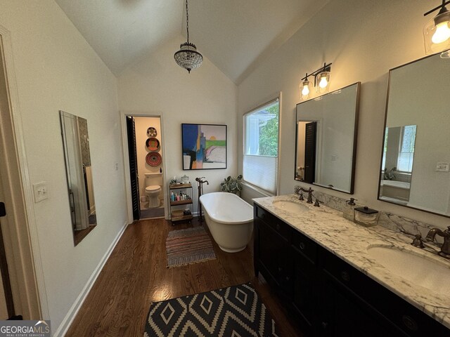 3146 Weymouth Dr, Marietta, GA 30062 - bathroom with wood finished floors, lofted ceiling, a freestanding tub, double vanity, and toilet