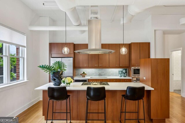1058 Piedmont Ave Unit 103, Atlanta, GA 30309 - kitchen with appliances with stainless steel finishes, island exhaust hood, brown cabinetry, light countertops, and a sink