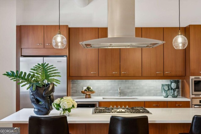 1058 Piedmont Ave Unit 103, Atlanta, GA 30309 - kitchen with island range hood, a sink, appliances with stainless steel finishes, light countertops, and brown cabinets