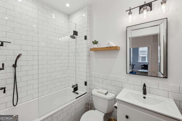 1058 Piedmont Ave Unit 103, Atlanta, GA 30309 - bathroom featuring tiled shower / bath combo, toilet, vanity, tile walls, and recessed lighting