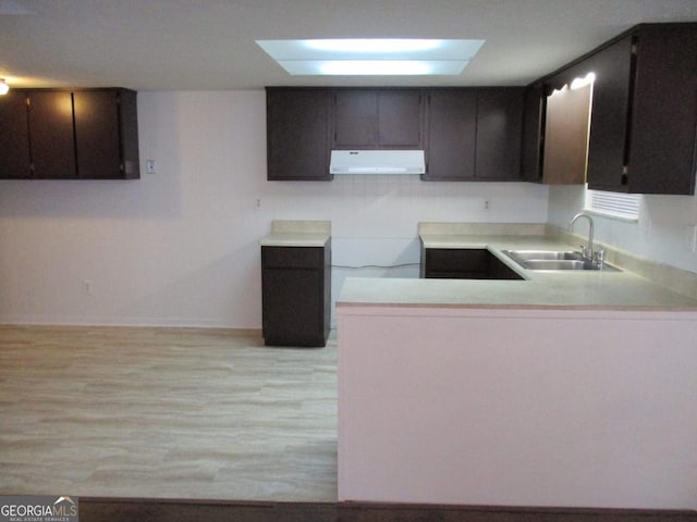 102 Westcliff Ctr Unit D, Warner Robins, GA 31093 - kitchen featuring ventilation hood, a sink, a peninsula, light wood-type flooring, and light countertops