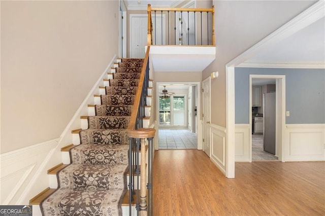 106 Waterford Pl, Acworth, GA 30101 - stairway featuring wood finished floors, ornamental molding, wainscoting, a ceiling fan, and a high ceiling