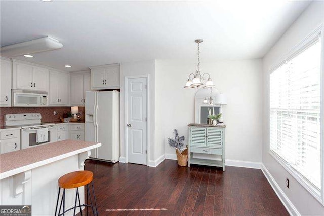 kitchen featuring white appliances, light countertops, white cabinets, dark wood-style floors, and baseboards