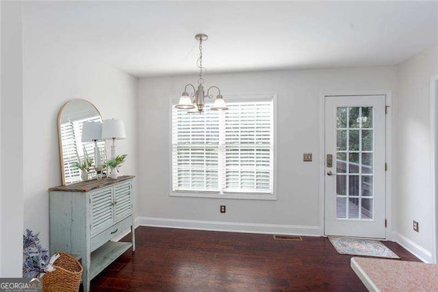 unfurnished dining area with a chandelier, wood finished floors, and baseboards