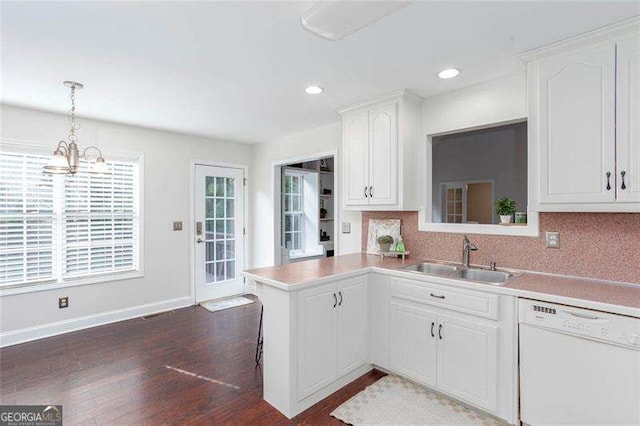 kitchen with white dishwasher, a sink, dark wood-style flooring, white cabinets, and a chandelier