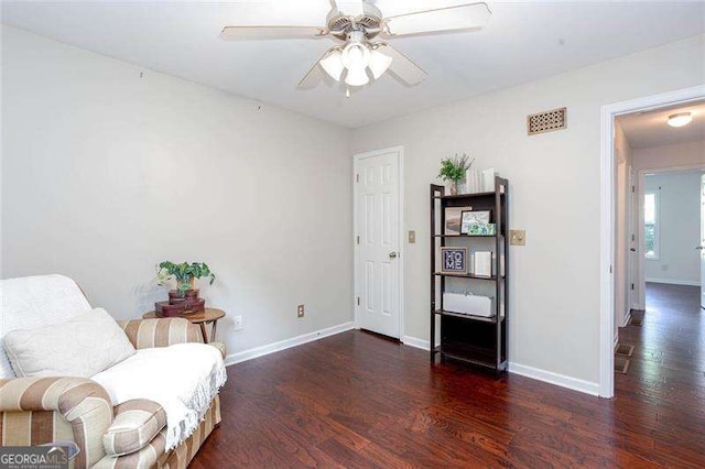 living area with wood finished floors, a ceiling fan, and baseboards