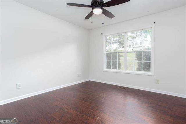 empty room featuring dark wood-style floors, baseboards, and a ceiling fan