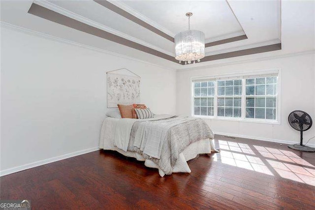 bedroom with a chandelier, a raised ceiling, crown molding, wood finished floors, and baseboards