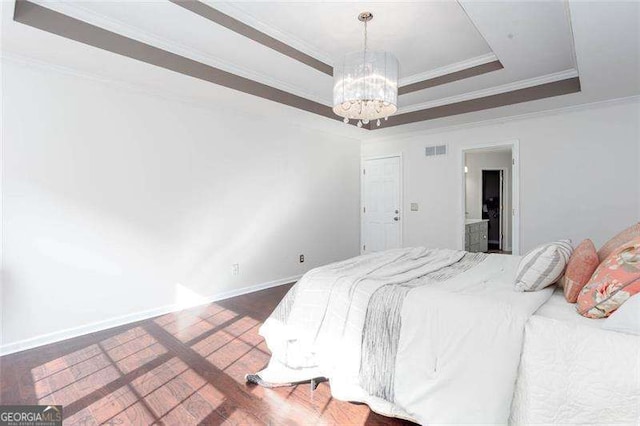 bedroom featuring a chandelier, ornamental molding, wood finished floors, a tray ceiling, and baseboards