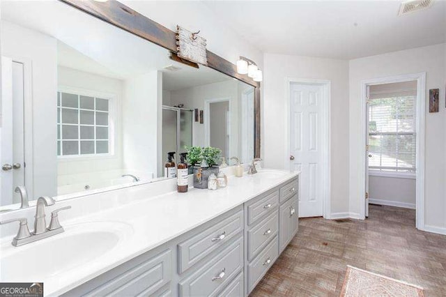 bathroom with baseboards, double vanity, wood finished floors, and a stall shower