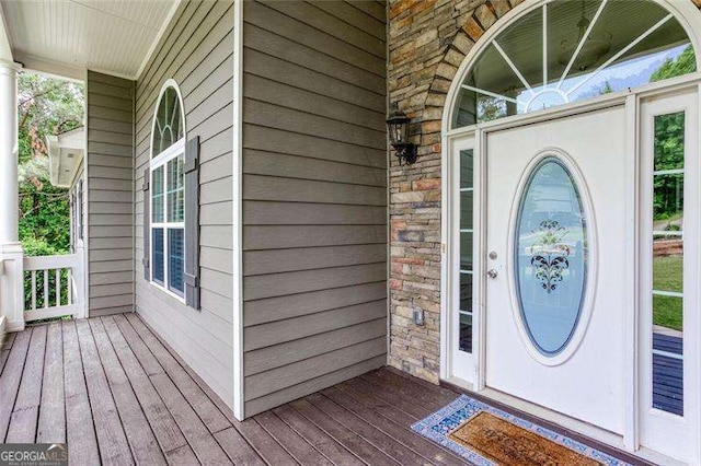 doorway to property with covered porch and stone siding