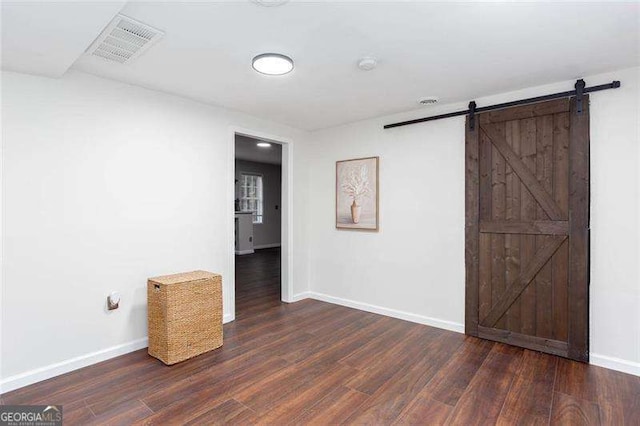 spare room with a barn door, wood finished floors, and baseboards
