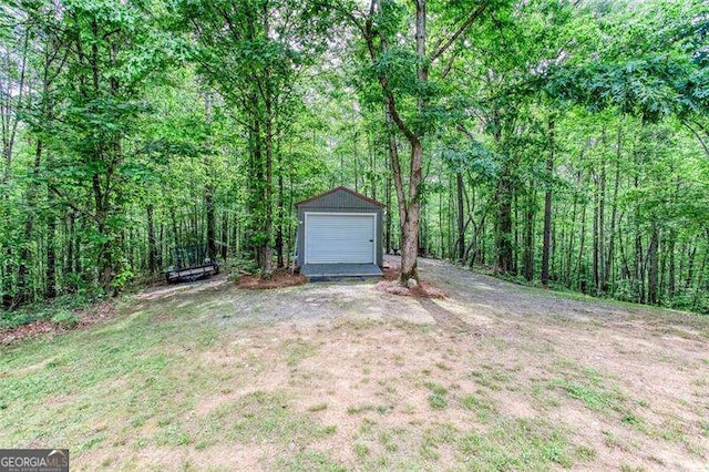 view of grassy yard with an outdoor structure and a view of trees