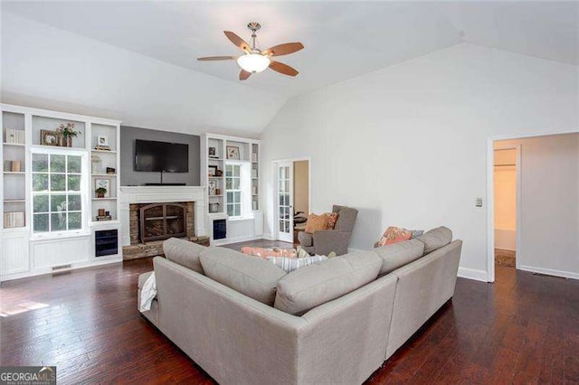 living area with vaulted ceiling, ceiling fan, hardwood / wood-style floors, a glass covered fireplace, and built in shelves
