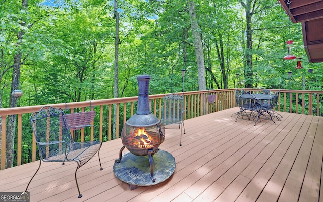 wooden deck with a fire pit and outdoor dining space