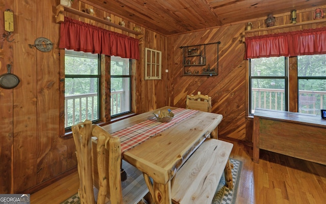 dining room with wood ceiling, healthy amount of natural light, wood walls, and wood finished floors