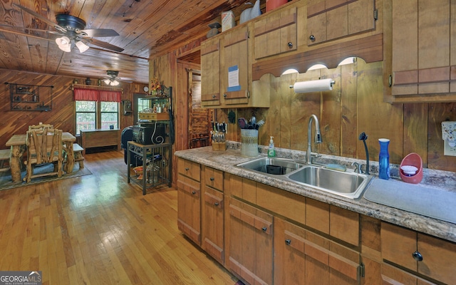 kitchen featuring a sink, wooden ceiling, wooden walls, light wood finished floors, and a ceiling fan