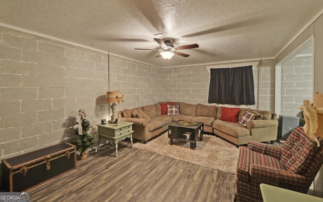 living area with a ceiling fan, concrete block wall, a textured ceiling, and wood finished floors