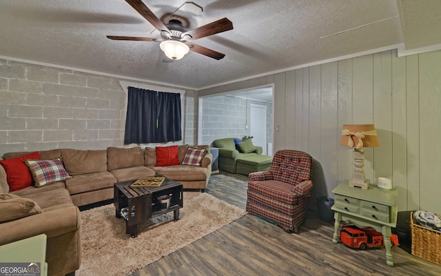 living area with wood finished floors, ceiling fan, a textured ceiling, and concrete block wall