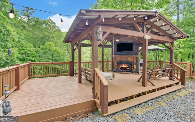 deck with a warm lit fireplace and a gazebo
