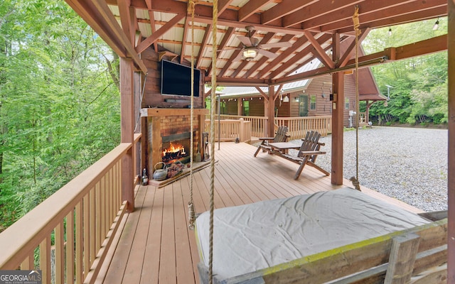 deck featuring an outdoor brick fireplace and ceiling fan