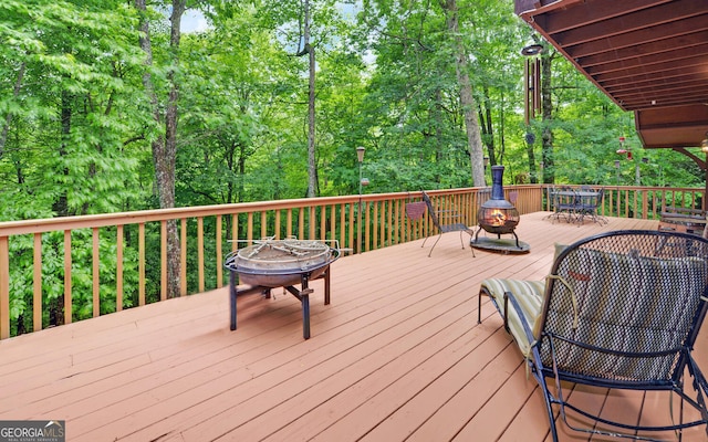 wooden terrace with an outdoor fire pit and outdoor dining space