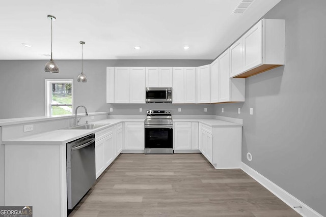 3614 Griffin Dr, Gainesville, GA 30506 - kitchen featuring stainless steel appliances, a sink, a peninsula, white cabinetry, and hanging light fixtures