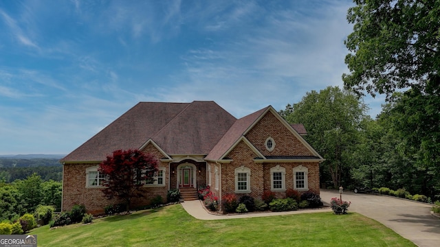 view of front facade featuring brick siding, a front yard, and driveway