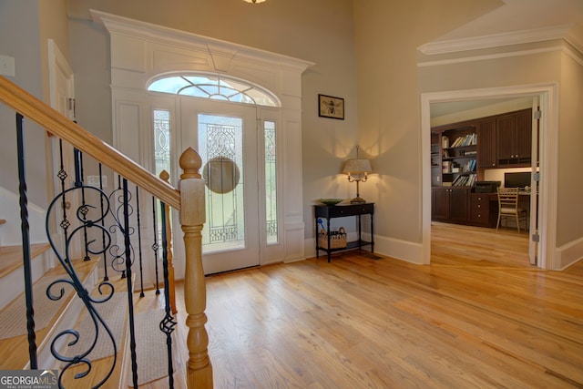 entrance foyer with stairs, light wood-style flooring, crown molding, and baseboards