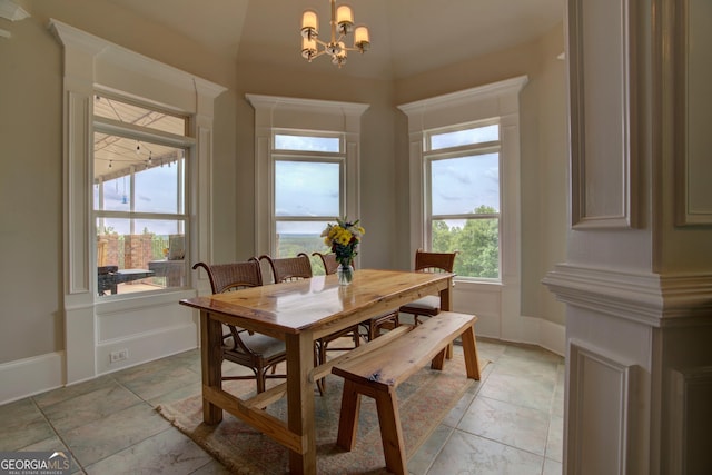 dining room featuring a chandelier, stone tile floors, and baseboards