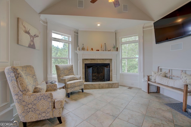 living area featuring lofted ceiling, a tiled fireplace, ceiling fan, and tile patterned flooring
