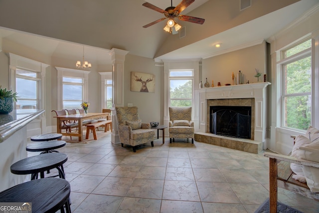 living area with a ceiling fan, a fireplace, lofted ceiling, and ornamental molding