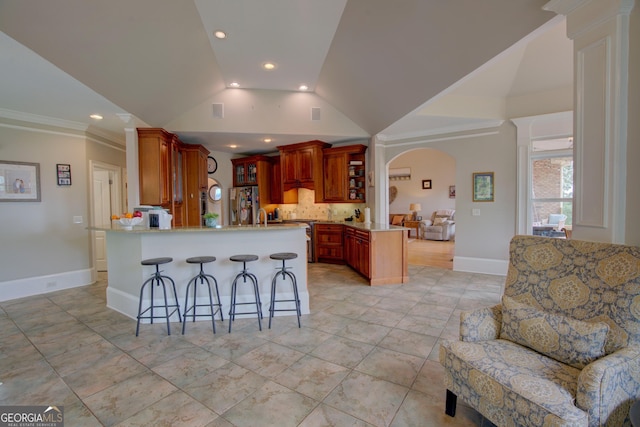 kitchen featuring a peninsula, stainless steel refrigerator with ice dispenser, decorative backsplash, a kitchen bar, and light countertops