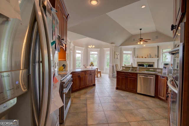 kitchen with stainless steel appliances, a peninsula, ceiling fan, open floor plan, and a fireplace