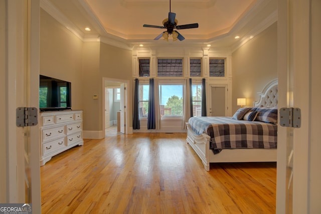 bedroom featuring crown molding, a high ceiling, a raised ceiling, light wood-style flooring, and recessed lighting