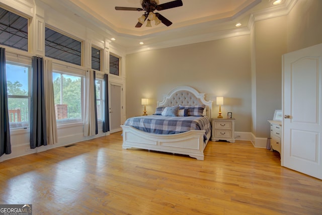 bedroom featuring crown molding, a high ceiling, light wood-type flooring, a tray ceiling, and recessed lighting