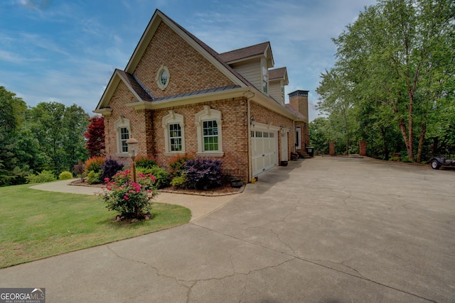 view of front of home with brick siding, concrete driveway, an attached garage, a front yard, and a standing seam roof