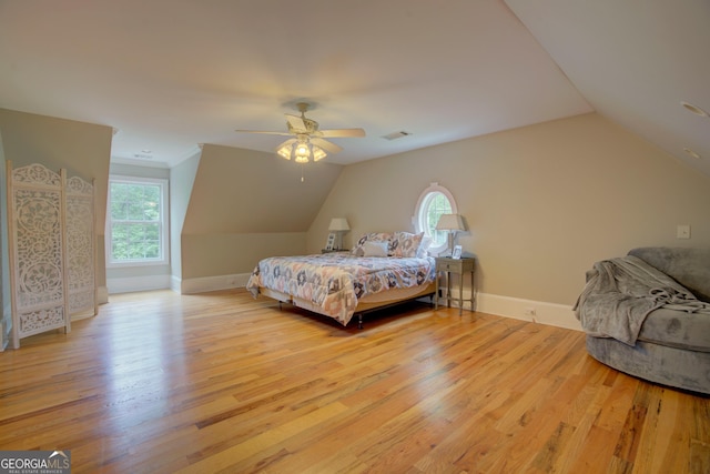 bedroom with light wood finished floors, vaulted ceiling, baseboards, and ceiling fan