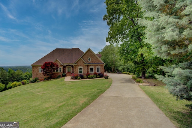 view of front of home with brick siding, a front lawn, and driveway