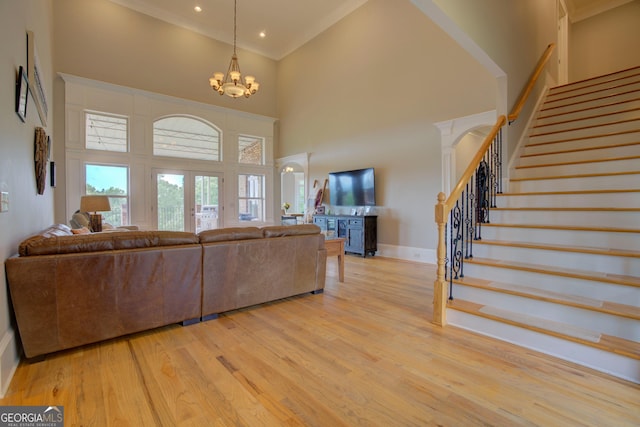 living room featuring a high ceiling, stairway, wood finished floors, baseboards, and a chandelier
