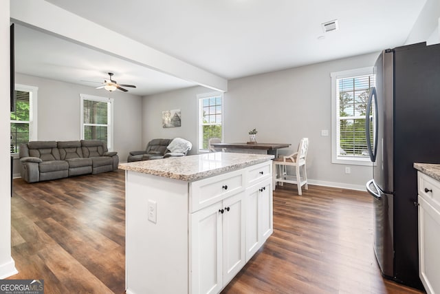 kitchen with freestanding refrigerator, healthy amount of natural light, dark wood-style flooring, and white cabinetry