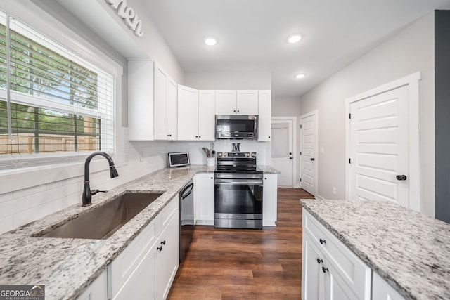 kitchen with stainless steel appliances, a sink, dark wood finished floors, white cabinetry, and light stone countertops